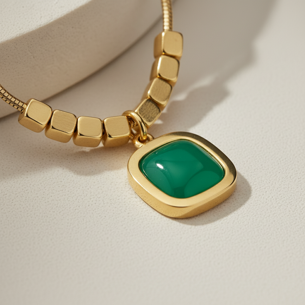 Minimalist gold plated snake chain necklace featuring a smooth square cushion-cut gemstone pendant and decorative cube beads. Available in Green, Peach, and Pink. Modern daily wear jewellery for women. Minimalist Necklace, Gold Plated Necklace, Square Pendant, Cushion Cut Necklace, Snake Chain, Cube Beads, Daily Wear Jewellery, Office Wear Necklace, Stone Pendant, Modern Necklace, Vrumaira, Surat Jewellery, Green Stone Necklace, Pink Stone Necklace, Peach Stone Necklace, Rose Quartz Look, Emerald Look